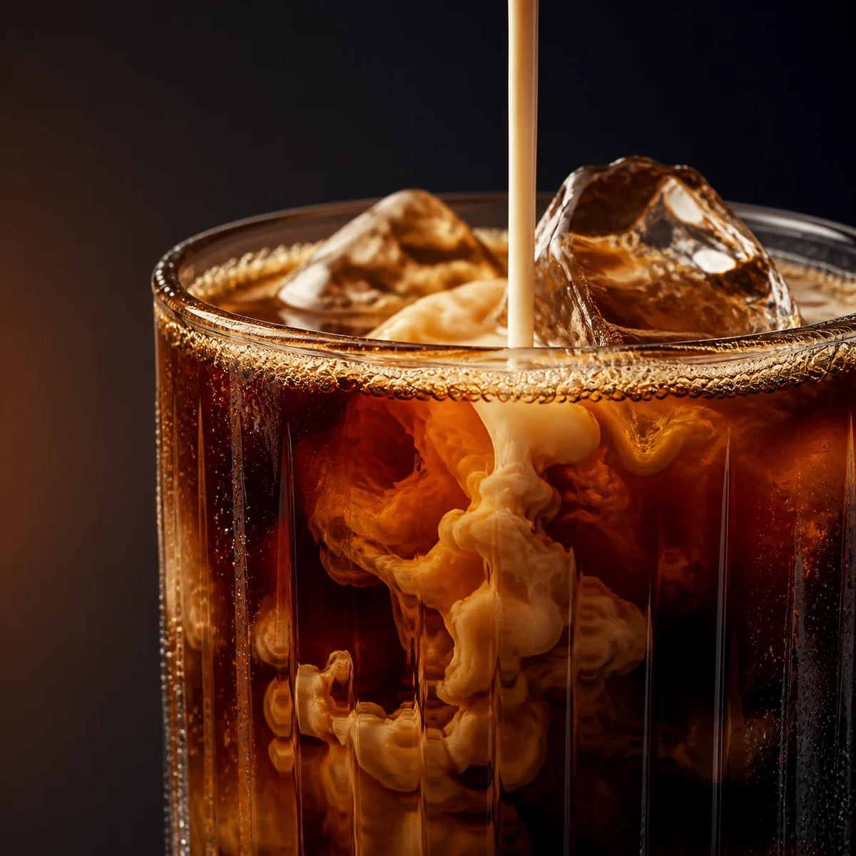 Macro of cream swirling into black coffee.