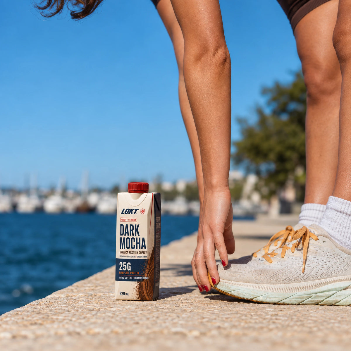 LOKT READY Dark Mocha beside a runner on a sunlit waterfront