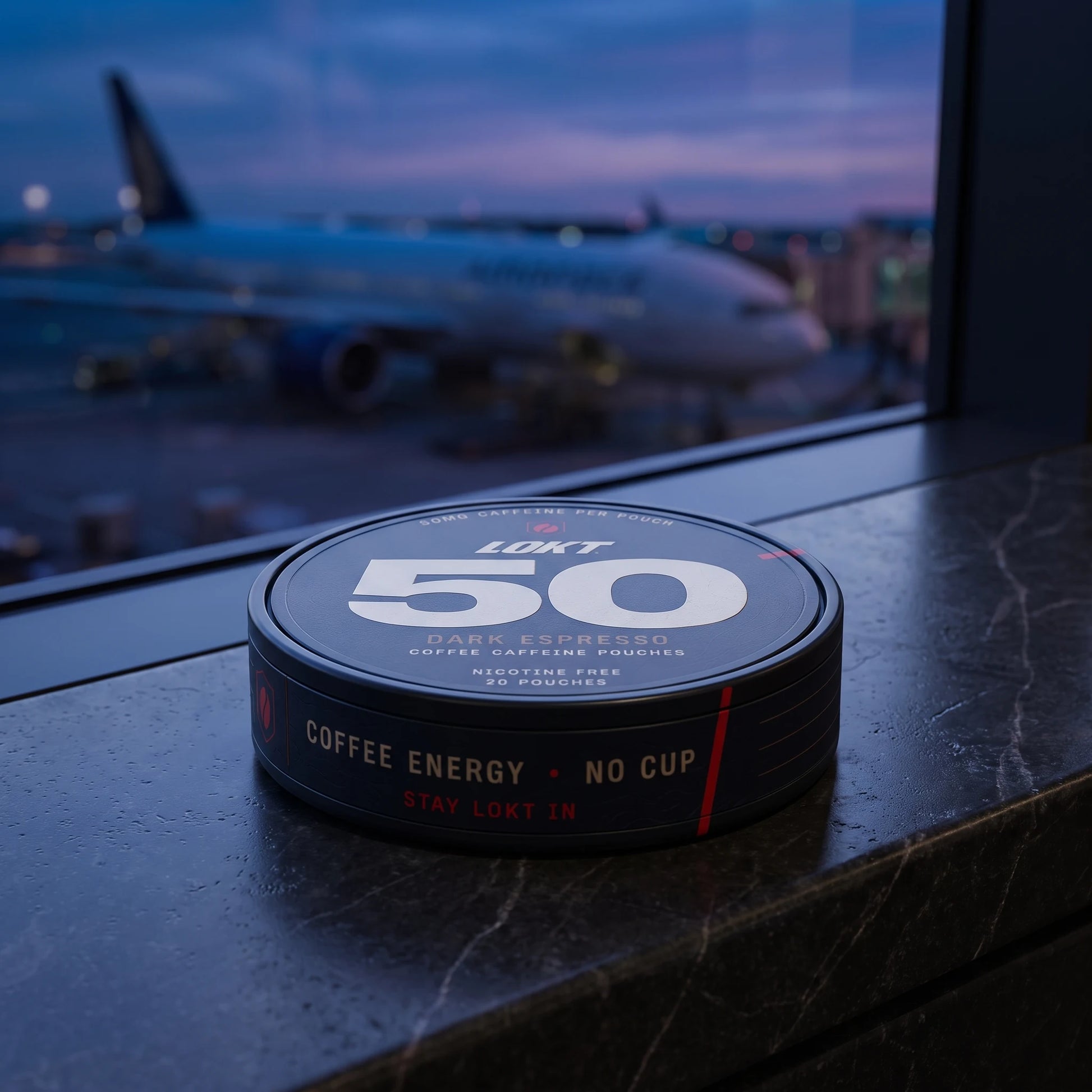 A LOKT 50 Dark Espresso can on an airport windowsill at blue hour