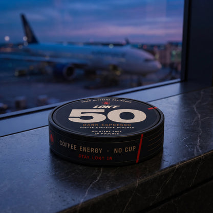 A LOKT 50 Dark Espresso tin on an airport gate ledge at blue hour