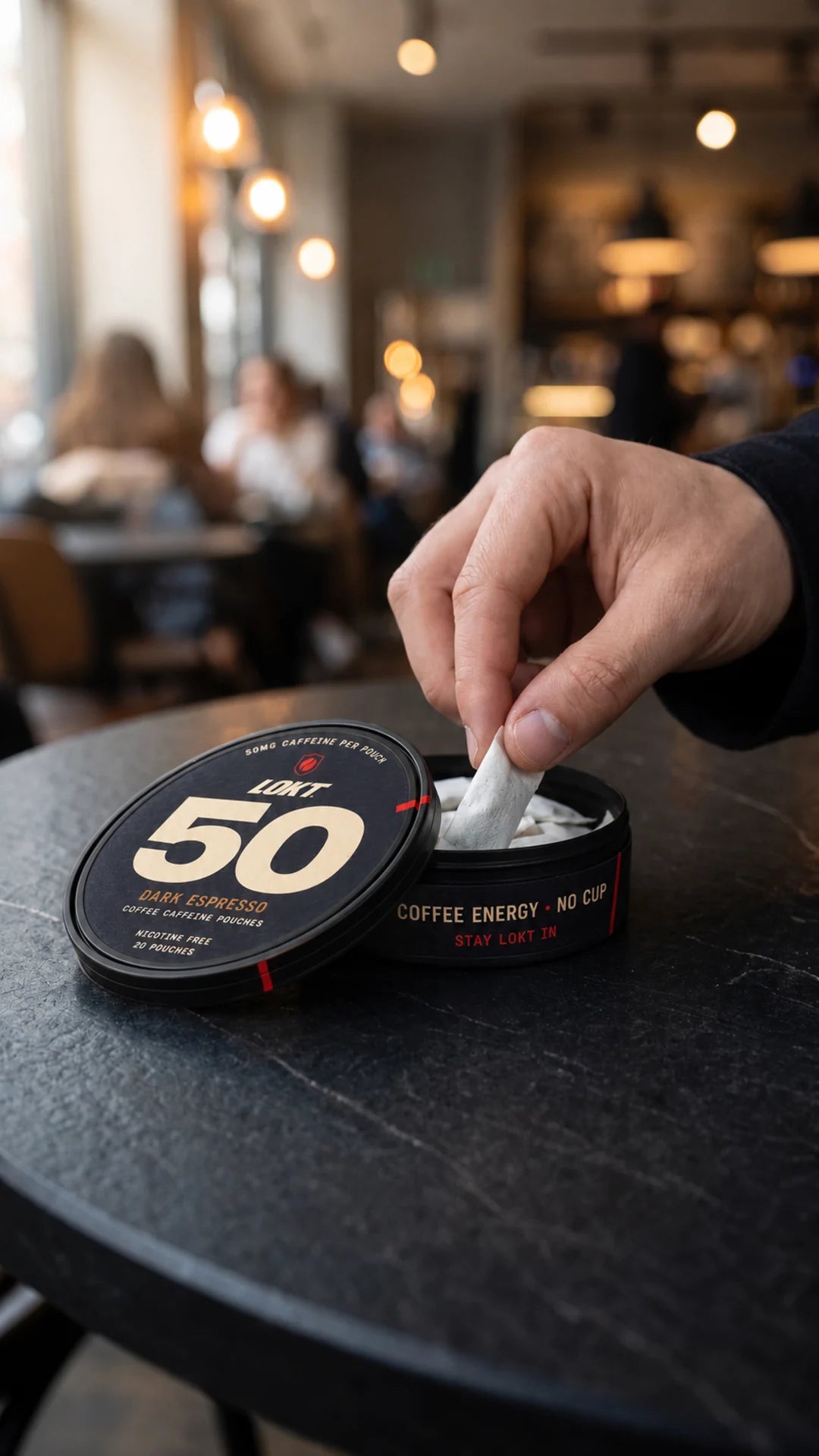 Taking a pouch from an open LOKT 50 Dark Espresso can at a cafe table