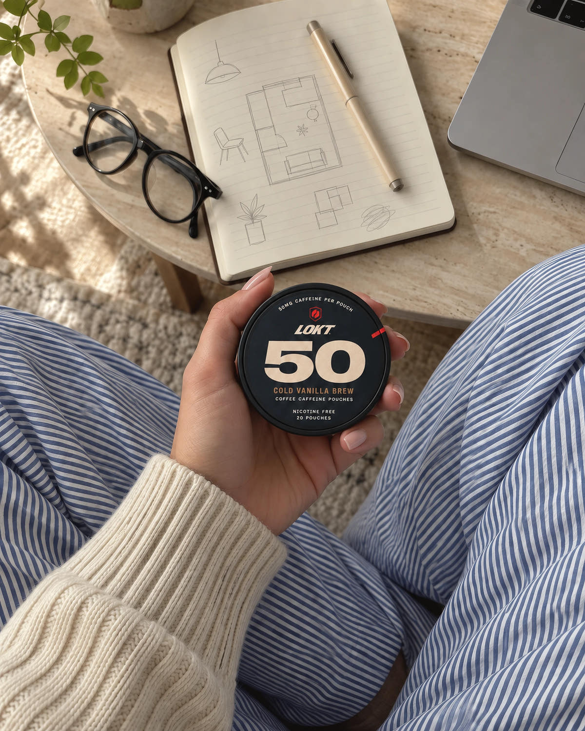 A Cold Vanilla Brew tin in hand beside a notebook and laptop