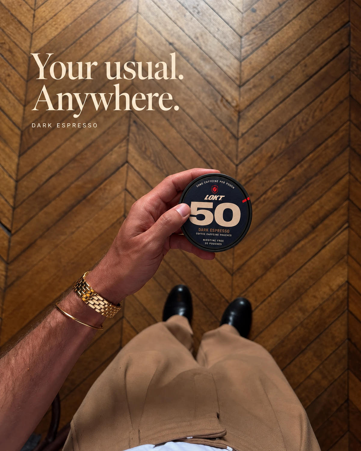 A closed Dark Espresso tin in hand above tan trousers and a sunlit parquet floor